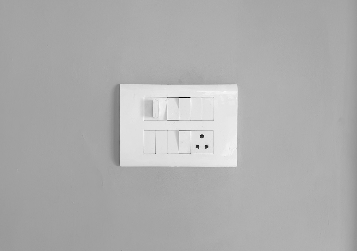Weißer Schaltschrank mit Kippschaltern an einer grauen Wand.