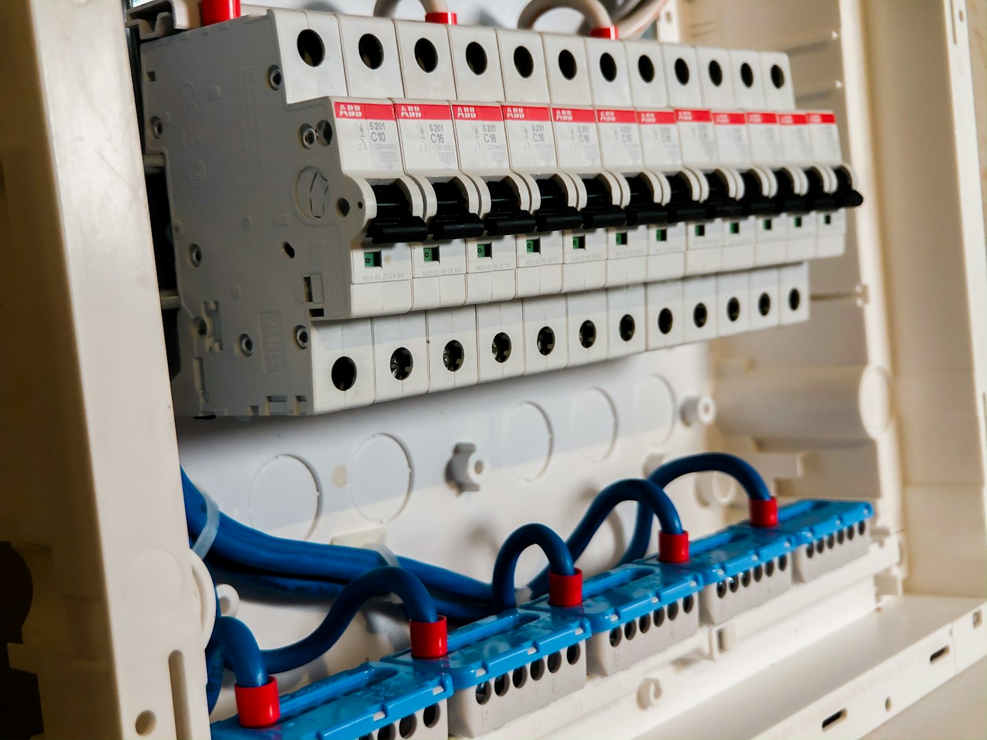 Elektrischer Verteilerkasten mit Reihen von Leistungsschaltern und blauer Verkabelung.