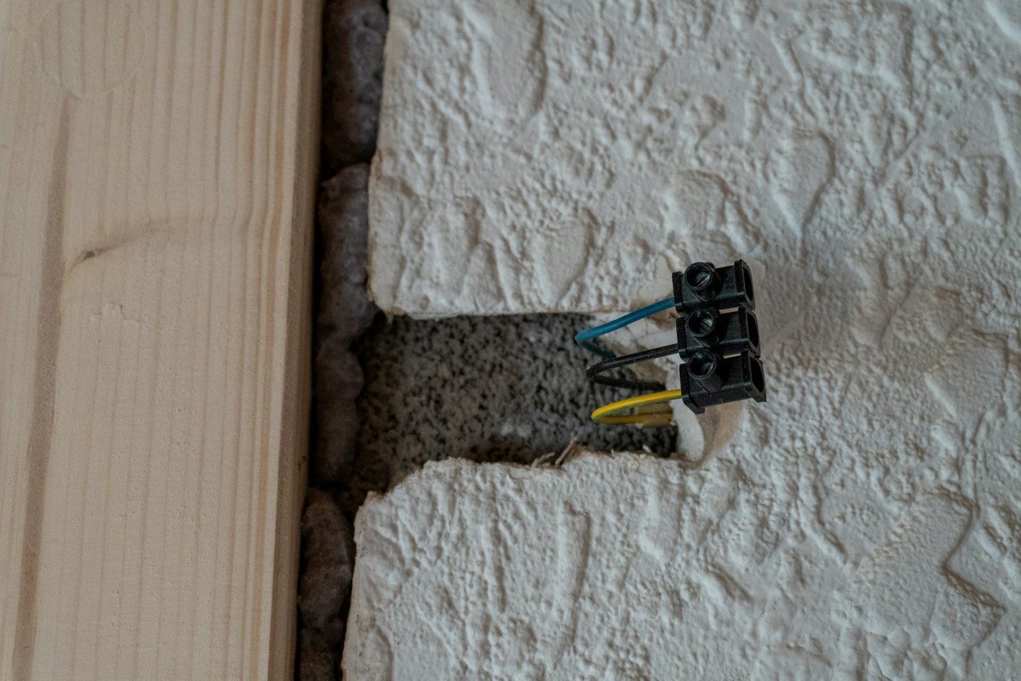 Elektriker installiert blaue und gelbe Kabel in einer Wand.