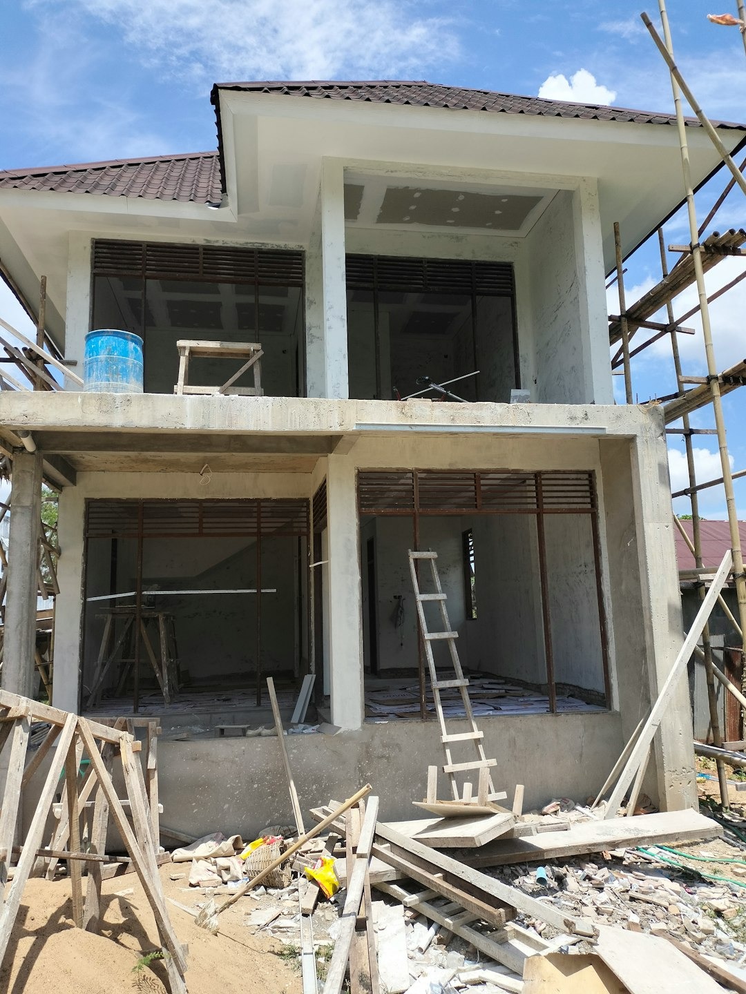 Two-story concrete house under construction with brown roof tiles.